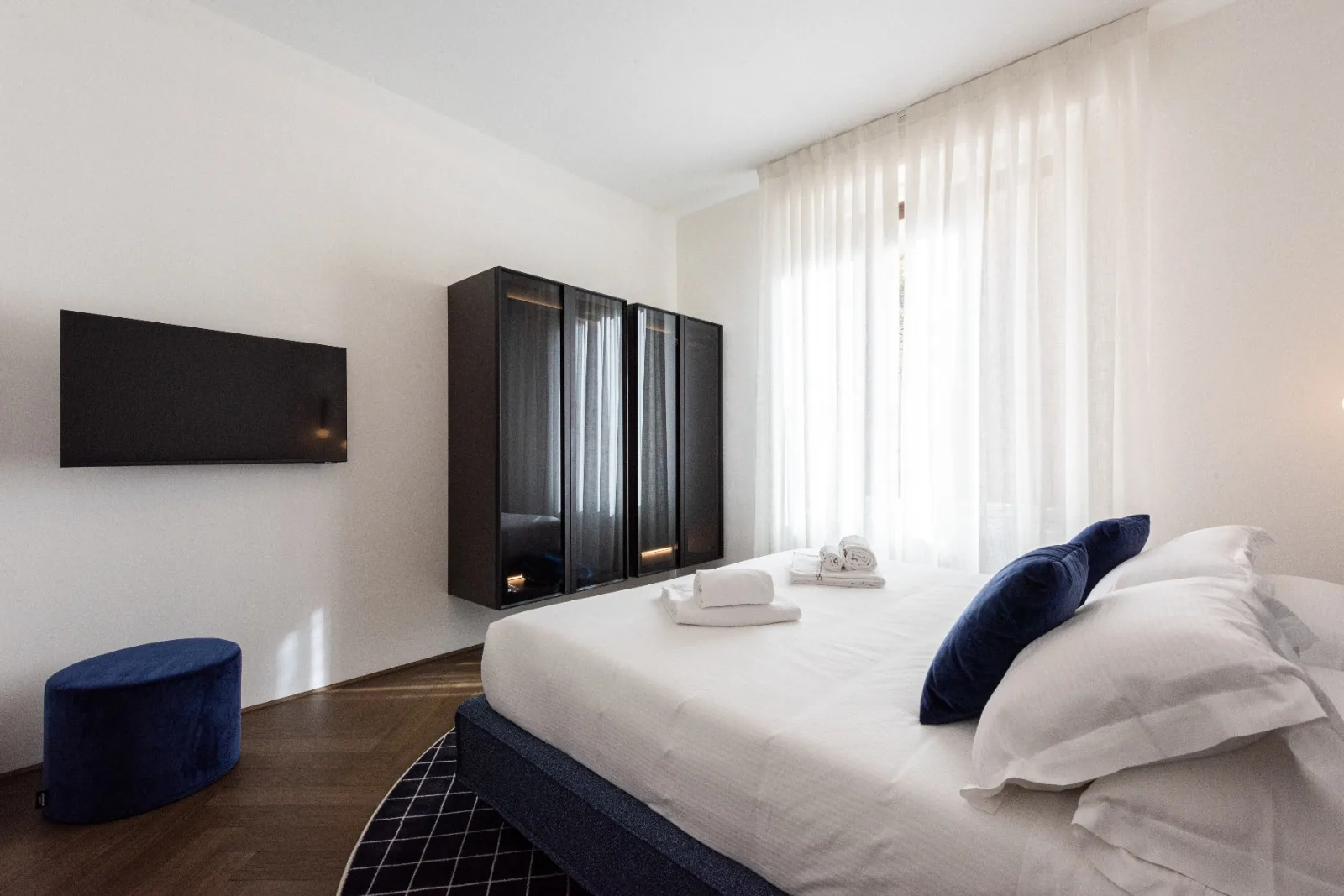 The first bedroom in a soft palette of white linen and navy velvet