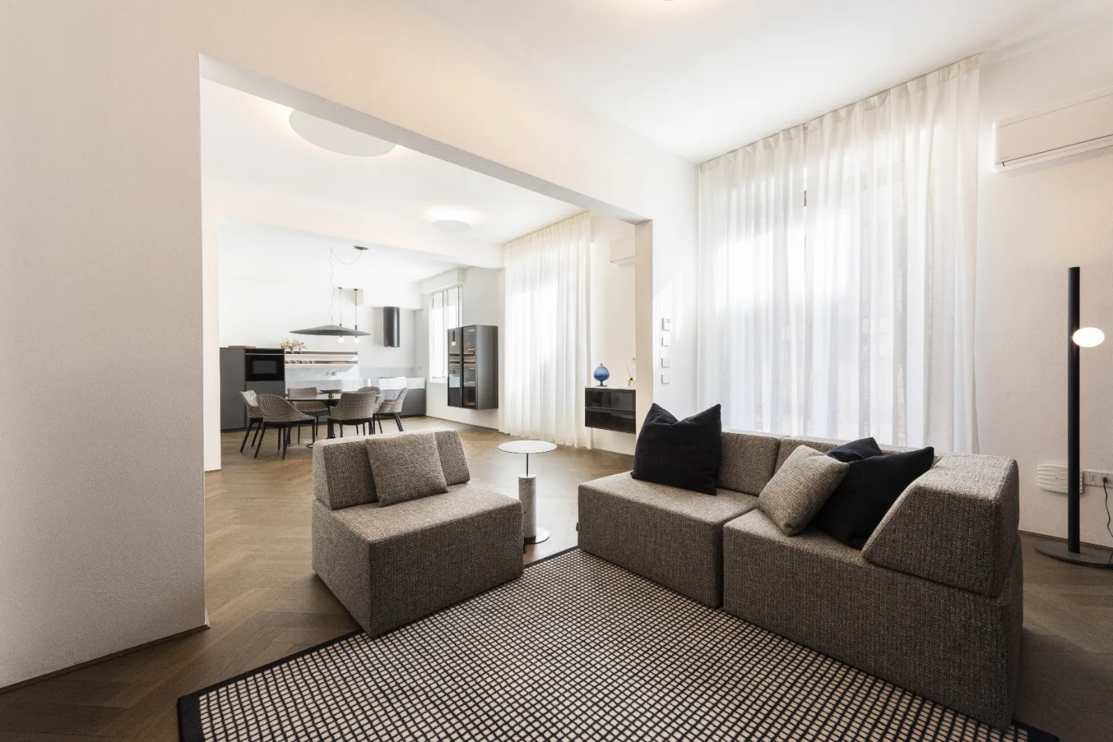 The main living room, bright and open, with bespoke grey sofas and herringbone parquet